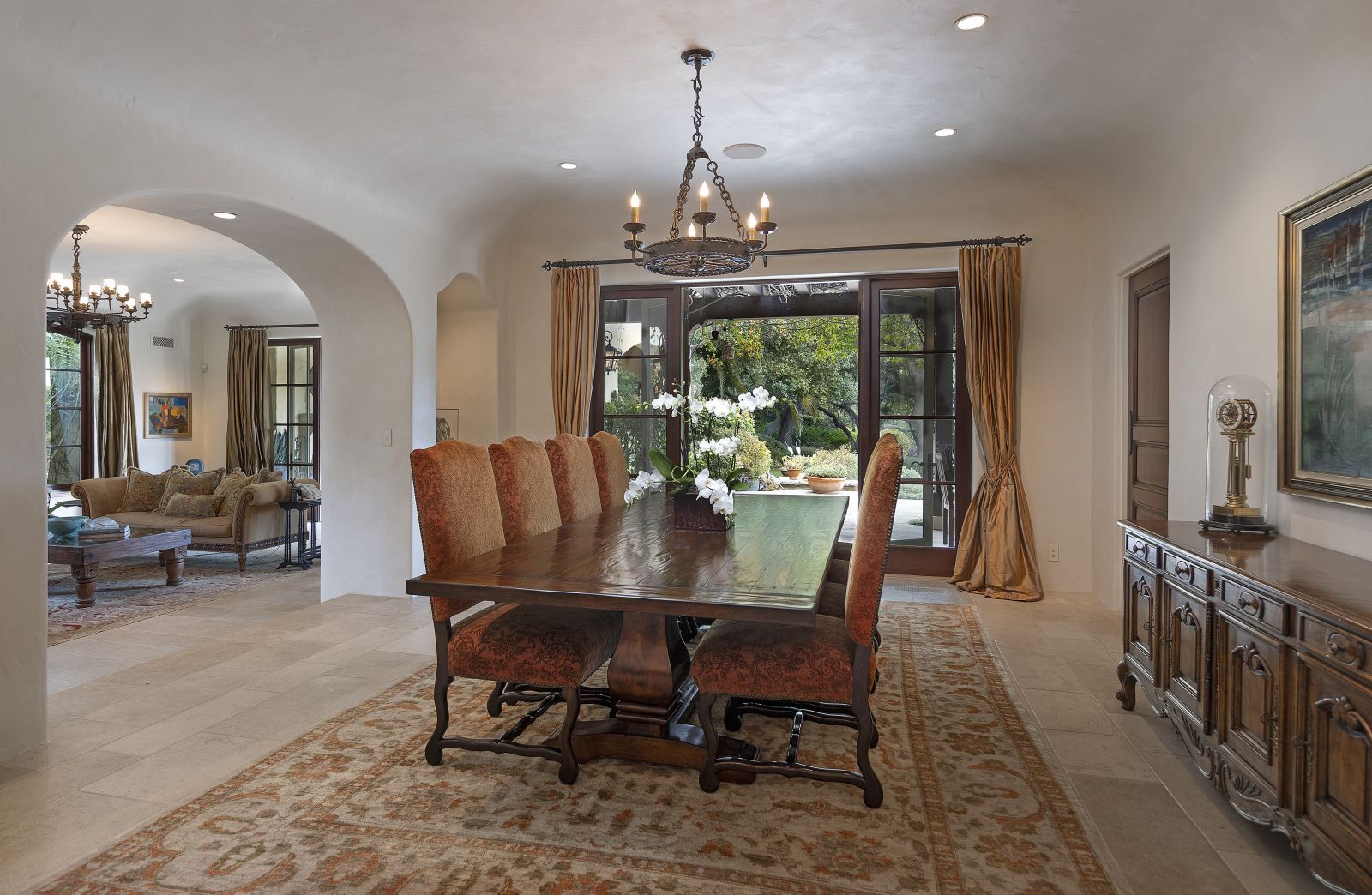 A grande double archway leads to a formal dining room with a chandelier and sliding doors to a pation.